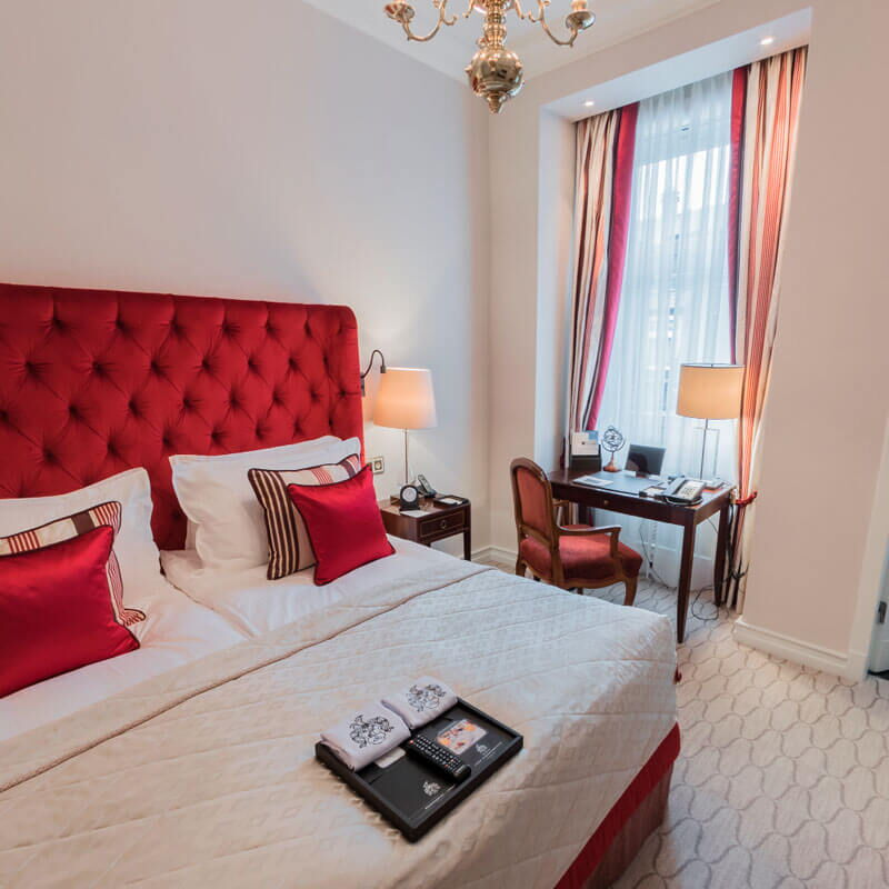 Rot dekoriertes Doppelbett im Doppelzimmer des Hotel Vier Jahreszeiten in Hamburg