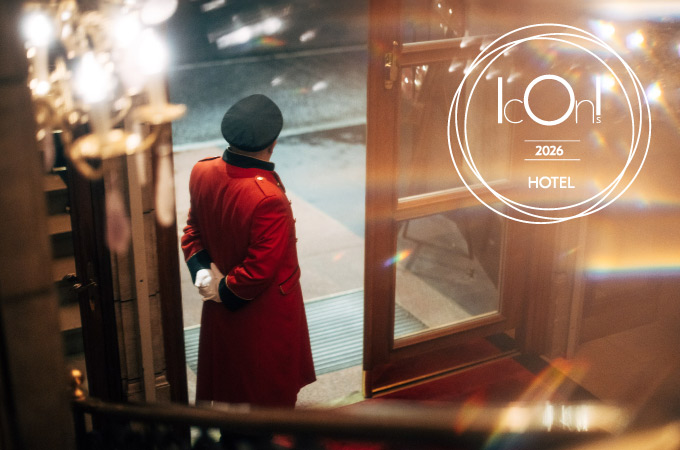 Gorgeous picture of the entrance to the Hotel Vier Jahreszeiten with the doorman from behind. On the right is the Icons Award that the hotel received in 2025.