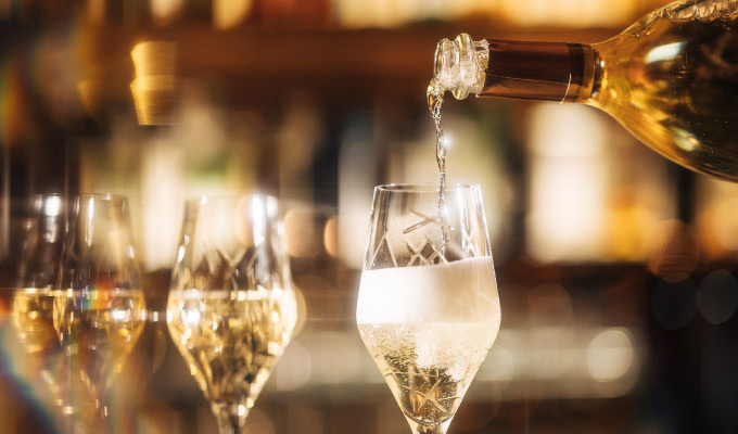 Close-up of several champagne glasses, with a glass being filled with champagne in the foreground