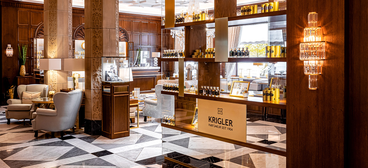 Holzvertäfelte Lobby mit Marmorboden und klassischer Einrichtung mit einem Parfümregal im Vordergrund der Marke Kriegler im Hotel Vier Jahreszeiten in Hamburg